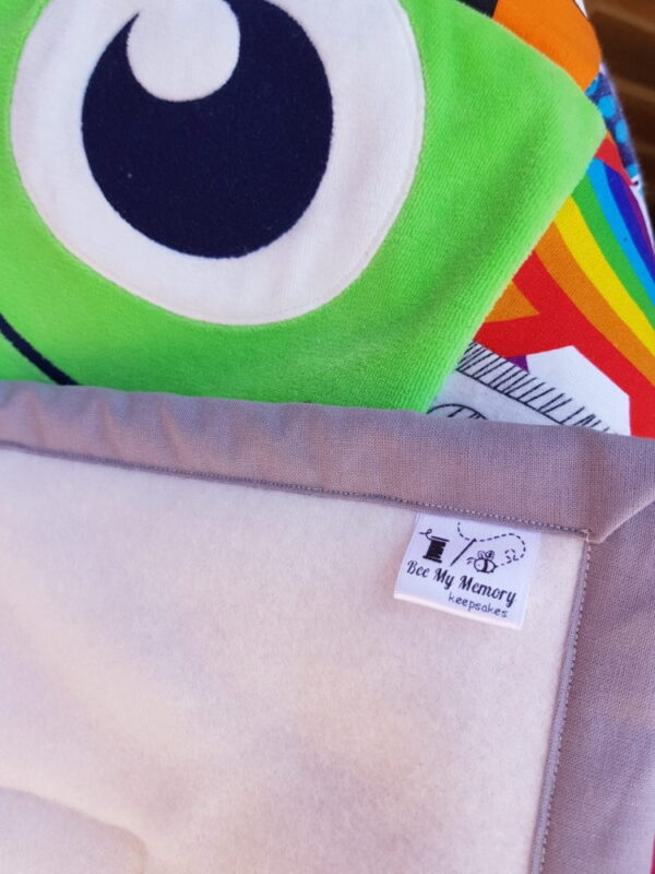 The corner of a memory blanket with fabric featuring a monster eyeball behind it