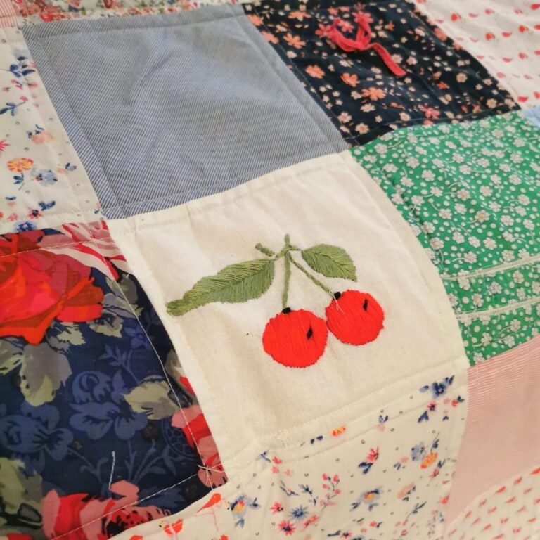 A patchwork blanket with a cherry in the centre square
