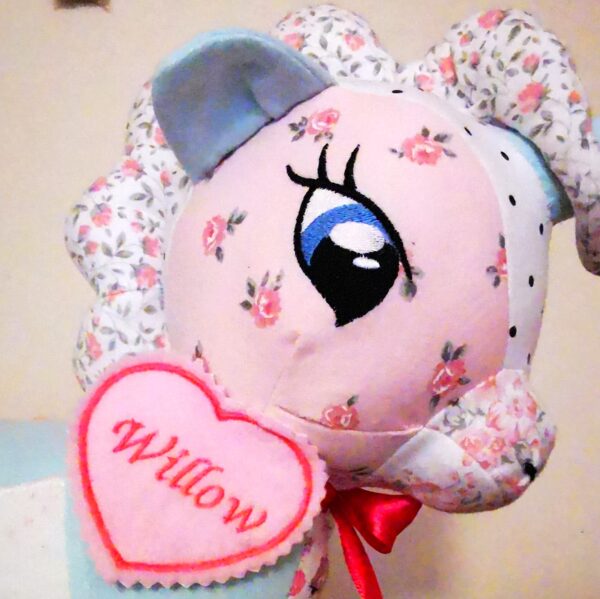 A keepsake memory unicorn with a pink head and a heart visible with 'Willow' sewn onto it