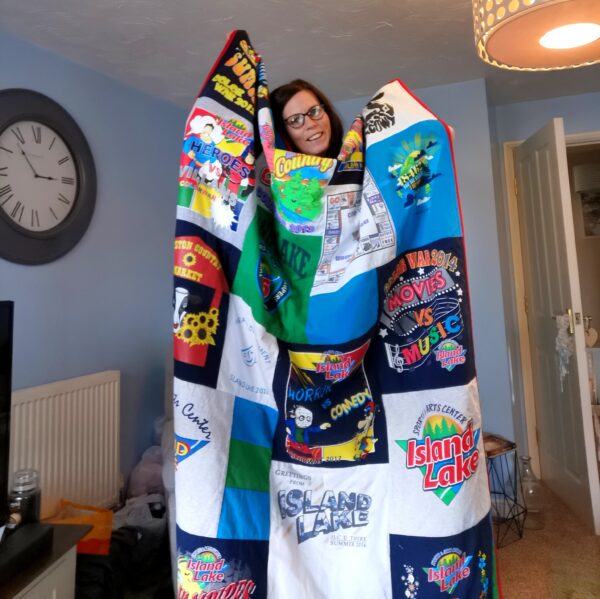 Bianca holding up a large blanket made from t-shirts