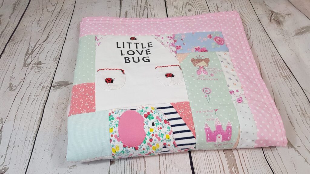 A folded memory blanket with the words 'little love bug' visible